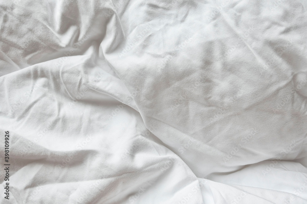 White Natural Cotton Sheet Bed Material Close-up. Unmade Hotel Bed Texture. Crumpled Messy Blanket In Home Bedroom.