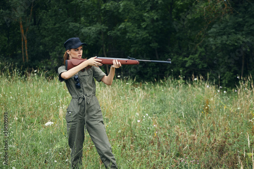Woman on nature Green overalls with a gun in front of him fresh air 