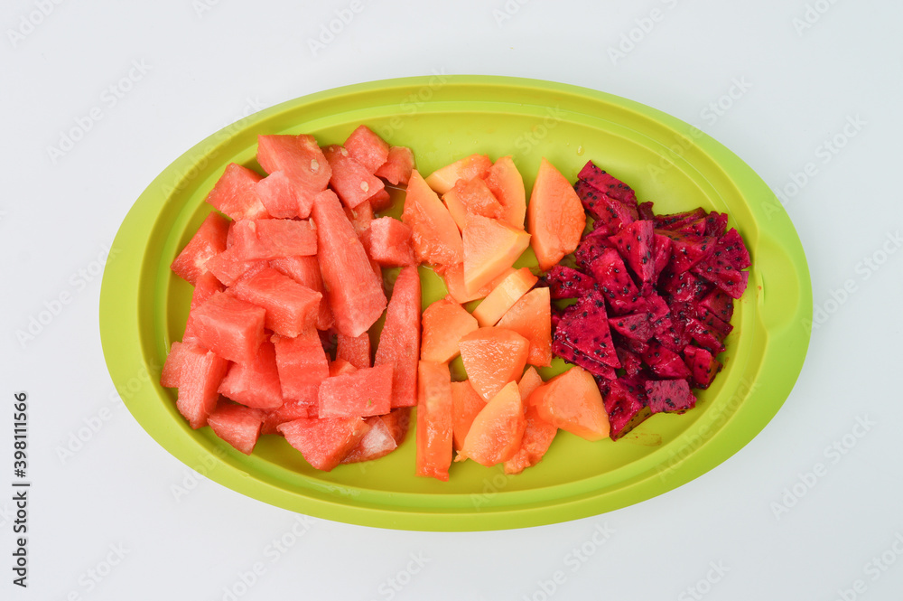 Top view of watermelons, papayas and dragon fruits assortment on a green plate. Tropical fruits on a white background. Top view of watermelons, papayas and dragon fruits assortment on a green plate. Tropical fruits on a white background.