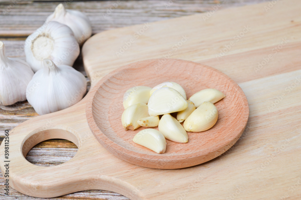 Fresh garlic on wooden plate isolated on wooden background. Selective focus.
Fresh garlic on wooden plate isolated on wooden background. Selective focus.