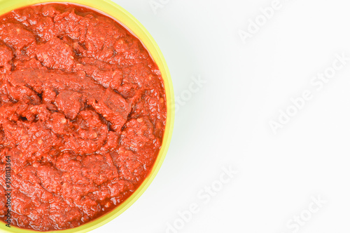The crop image of grinded chili pepper in a green bowl isolated on a white background.