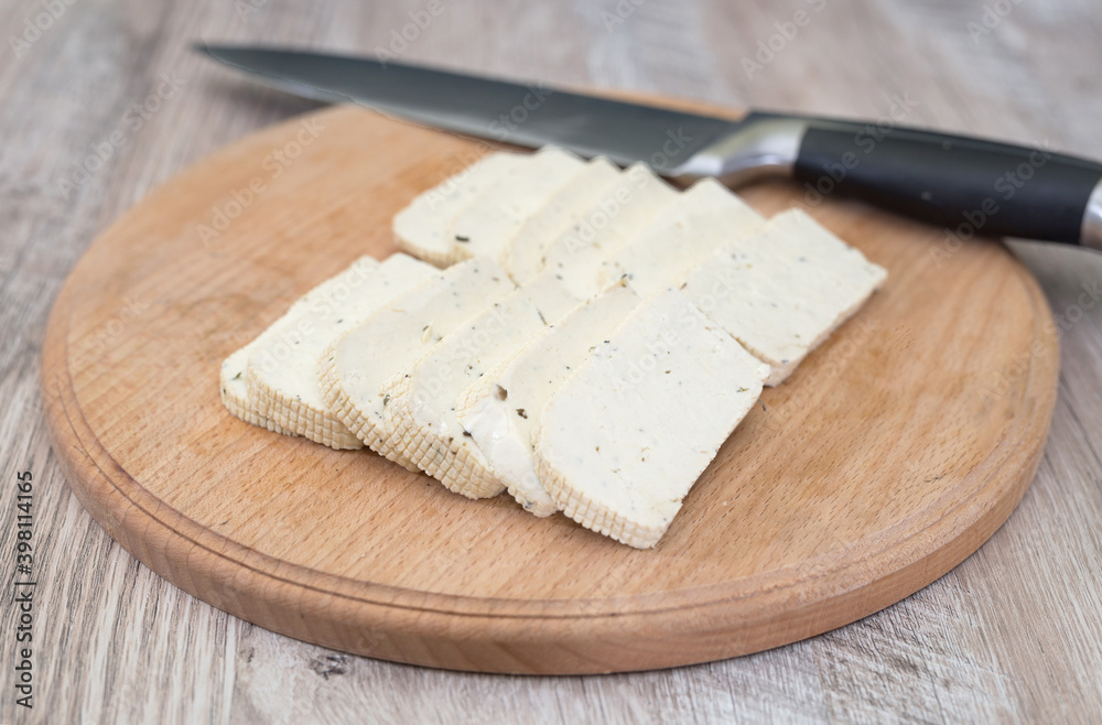 tofu cheese on a wooden board and a knife.