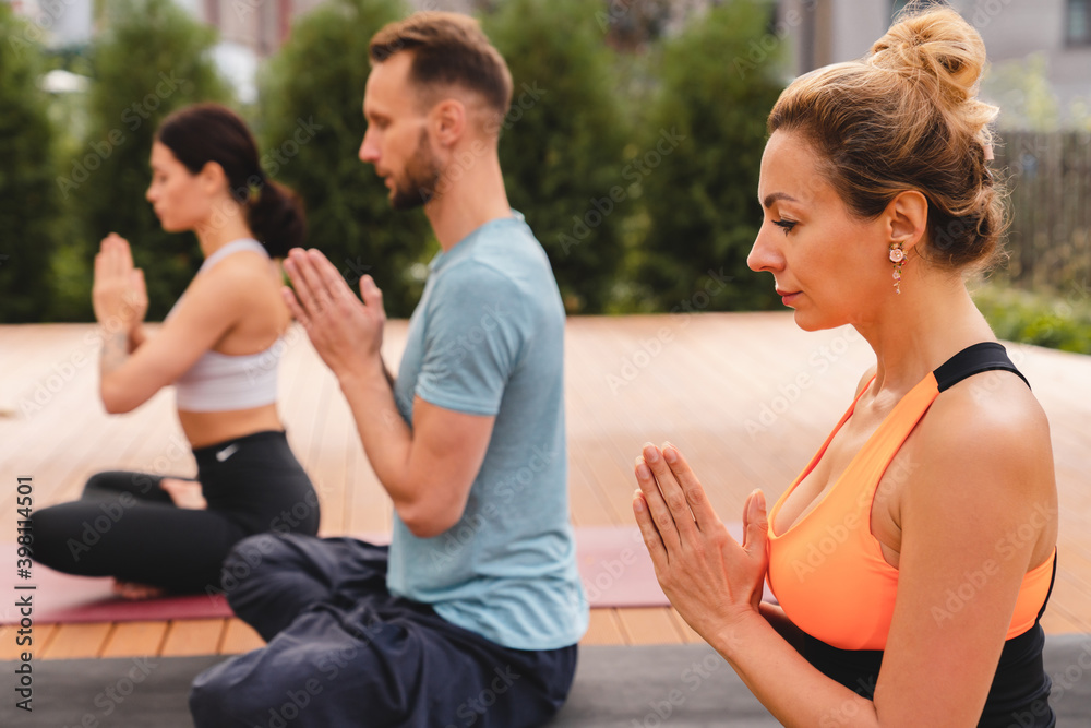 Sporty people meditating in yoga class together outside