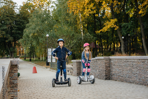 Happy boy and girl ride Segways in the Park on a warm autumn day during sunset. Rest, and walk.
