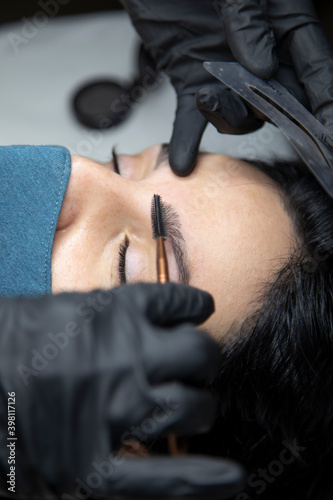 A beautician combing an eyebrow.