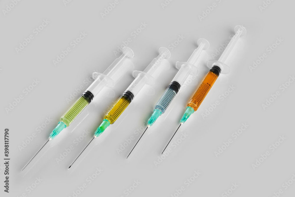 close-up of four syringes with colored vaccine close-up of four syringes with colored vaccine