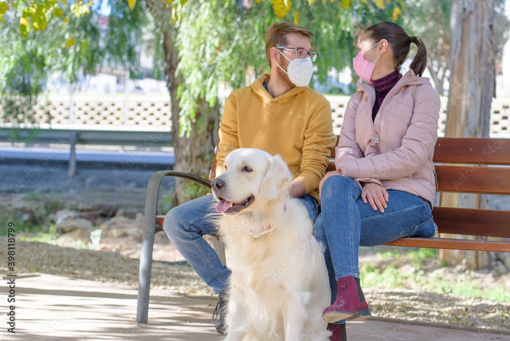 Young white couple in medical surgical masks holding walks with dog in the summer forest. family, europe, hugs, coronavirus, illness, infection, quarantine, virus, pet domestic isolation Young white couple in medical surgical masks holding walks with dog in the summer forest. family, europe, hugs, coronavirus, illness, infection, quarantine, virus, pet domestic isolation