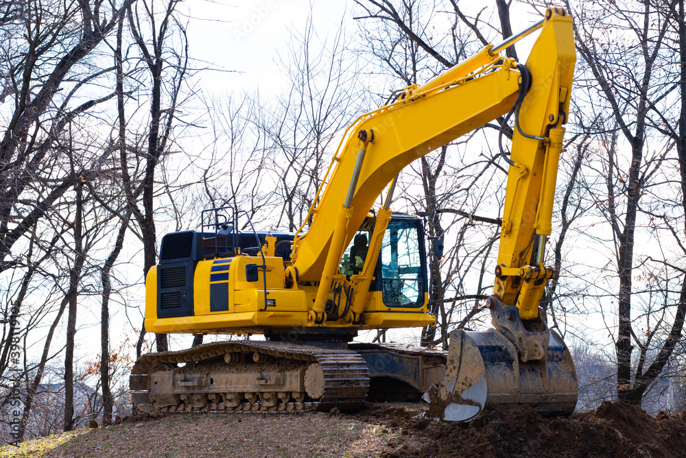 A large construction excavator of yellow color on the construction site