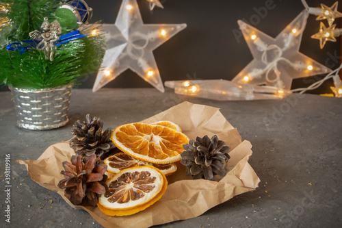 Slices of dried oranges, lemons and pine cones on dark table with New Year's garland. Christmas composition, postcard. Selective focus, festive mood