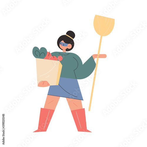Mother in superhero mask standing with shopping bag and household in hands