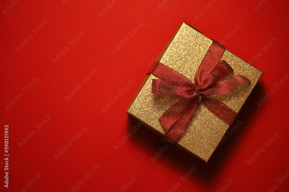 golden gift box with red ribbon on red background
