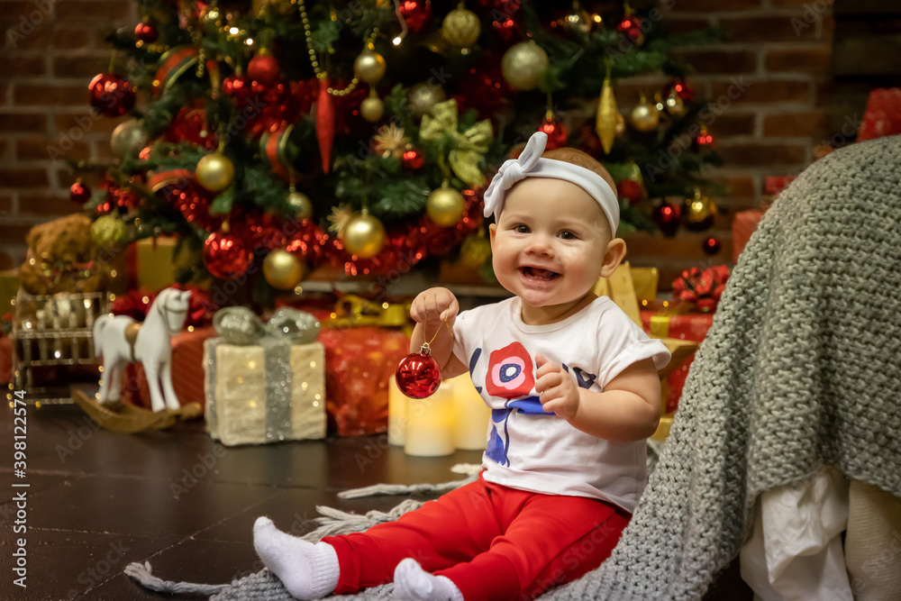 Cute baby girl sitting with Christmas Ball near Christmas trees at home, Happy New year
