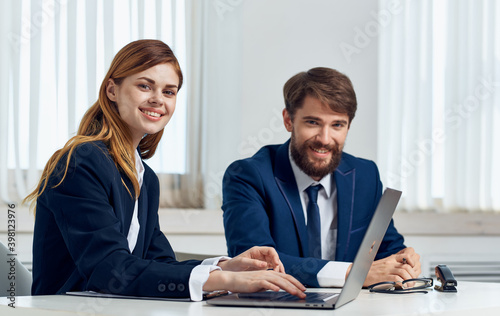 Business woman in suit and employee in office at table open laptop working finance