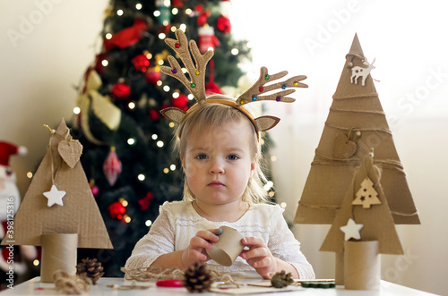 Funny child girl making decorations for christmas Handmade Christmas trees from natural materials. Concept of winter kids creativity and christmas crafts, eco friendly Christmas tree  photo