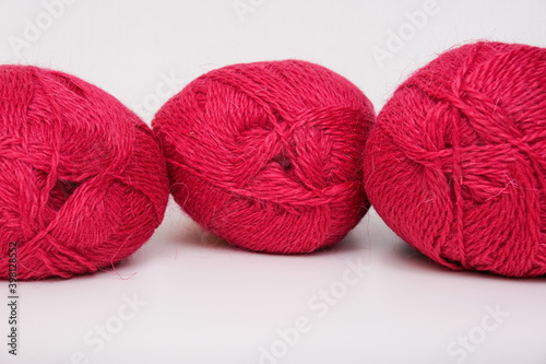 Red pink colorful skeins of yarn close up, fuchsia color woolen yarn for crochet and knitting, hobby and handmade concept