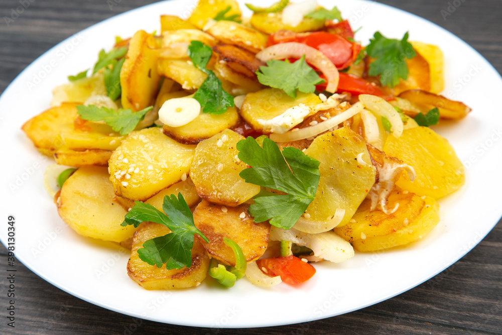 cooked fried potatoes with herbs and vegetables in a white plate on a wooden table cooked fried potatoes with herbs and vegetables in a white plate on a wooden table