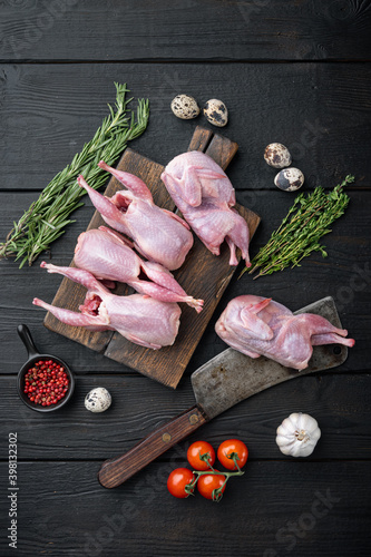 Fresh raw meat quails with herbs, flat lay, on black wooden background