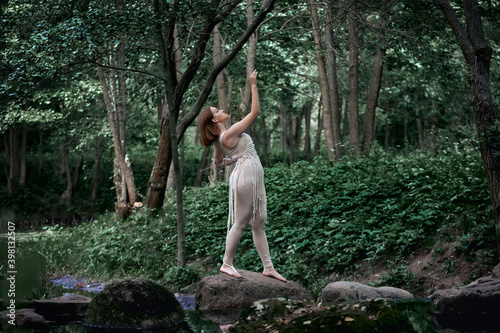 A young beautiful woman in a dress stands barefoot on a rock and dances. The concept of balance  natural cosmetics and health.