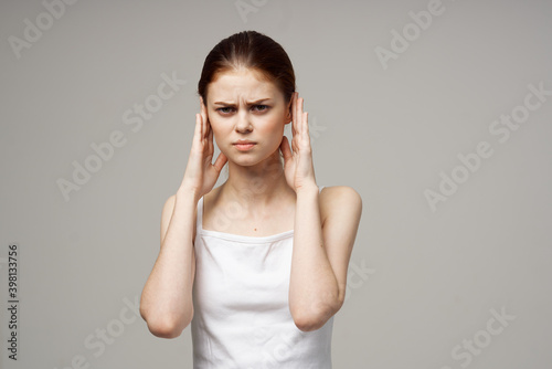 woman in white t-shirt holding ears discontent migraine health problems