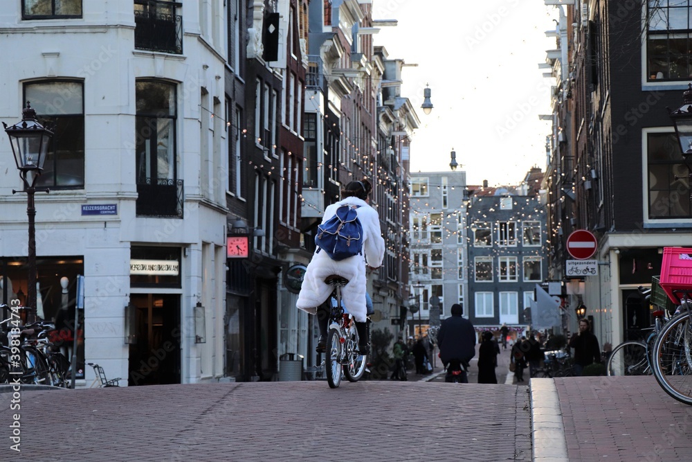 Street View in Amsterdam with Man in White Coat Riding on a Bike