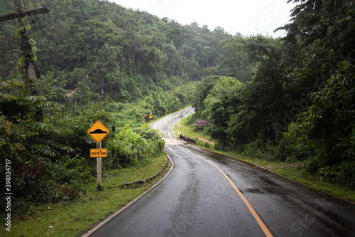 kurvige regennasse Strasse führt bergauf durch den grünen dunstigen Djungel in Nord Thailand - ein gelbes Schild warnt vor Bodenwellen - Mae Hong Son Loop 