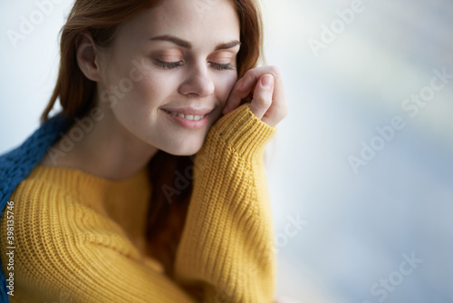 pretty woman in a yellow sweater hiding behind a blanket near the window comfort home interior