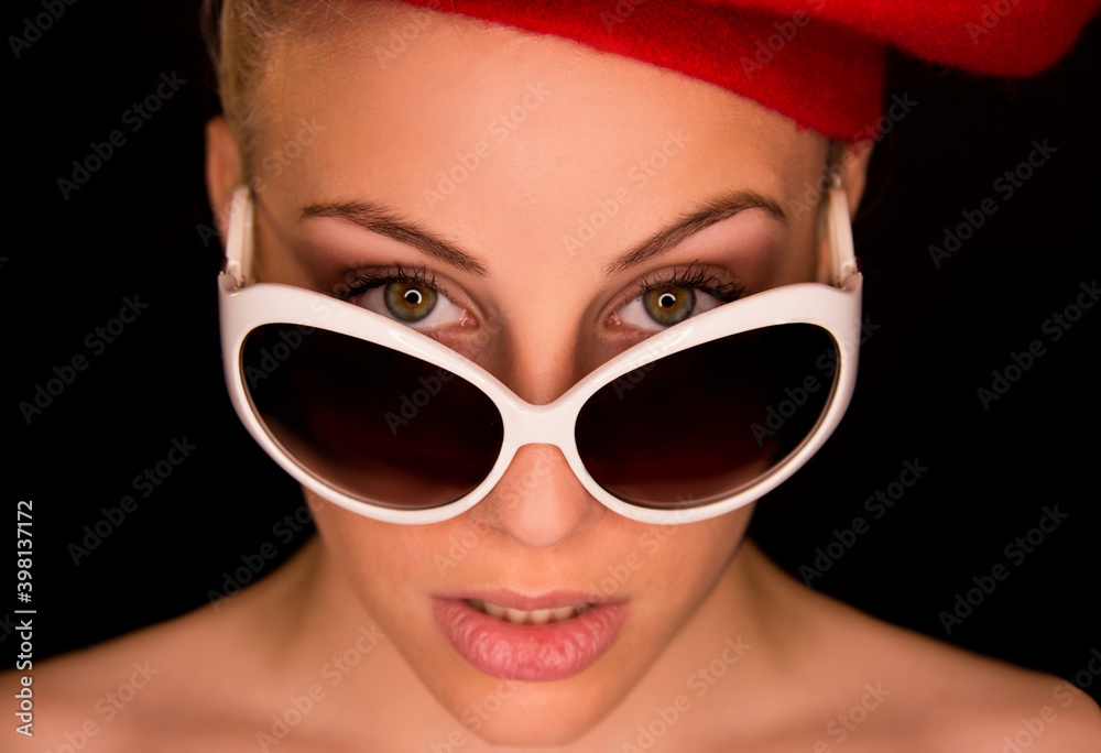 Young blonde girl close up with white sun glasses and red beret on dark background. Young blonde girl close up with white sun glasses and red beret on dark background.