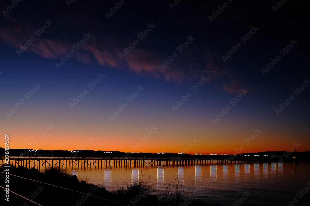 Twinkling lights on pier and spectacular sunrise.  White Rock, BC