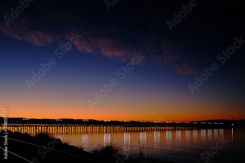 Twinkling lights on pier and spectacular sunrise. White Rock, BC