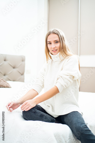 Close up portrait of blonde young woman wearing sweater at home