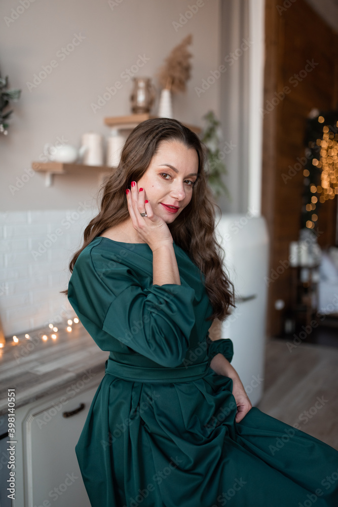 Portrait of a woman in a green dress against the background of Christmas garlands.