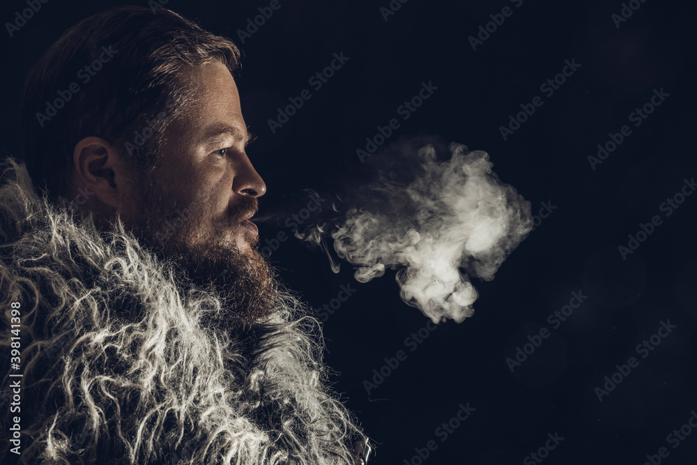 Solid bearded man dressed in a fur mantle exhaling vapour
