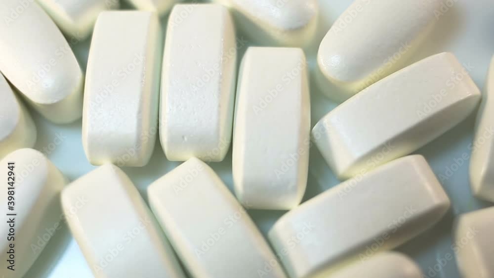 Beautiful light beige large long pills in a shiny shell move smoothly in the frame. Stabilization, white background, close-up, camera movement, real time, medicine Beautiful light beige large long pills in a shiny shell move smoothly in the frame. Stabilization, white background, close-up, camera movement, real time, medicine