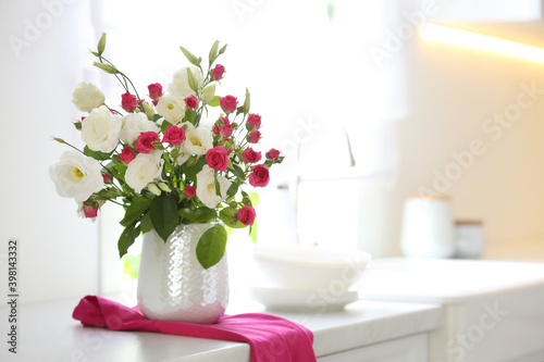 Vase with fresh flowers on table in kitchen. Space for text