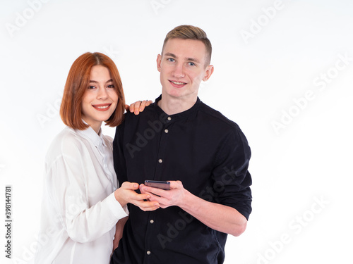 Portrait of a man and a woman. Guy and girl on a white background. Man and a woman are looking at camera. Concept - a girl and her boyfrend. Portrait of lovers with a phone in their hands. photo