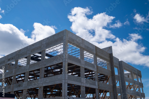 Multiple story precast grey concrete building with steel beams. The industrial structure in the corner of a skyscraper building with prefabricated engineering formwork. The sky is in the background. photo