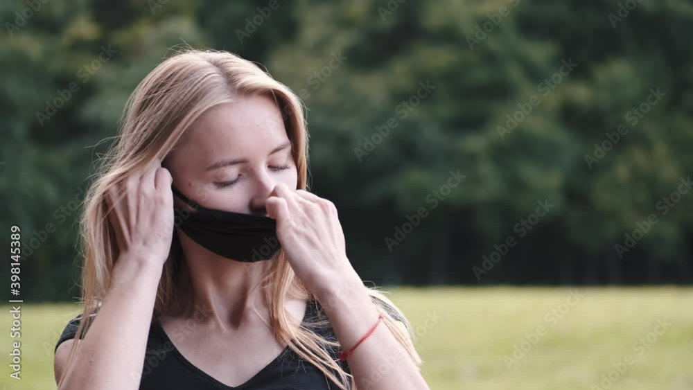 European young woman putting on mask on face. Wearing corona virus prevention masks for long hours are creating irritation, skin problems, acne pimples. European young woman putting on mask on face. Wearing corona virus prevention masks for long hours are creating irritation, skin problems, acne pimples.
