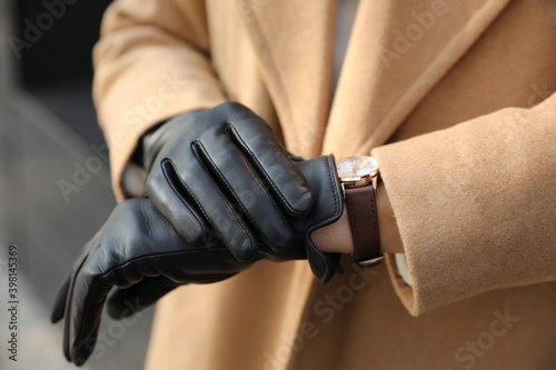 Woman in stylish leather gloves checking time outdoors  closeup of hands