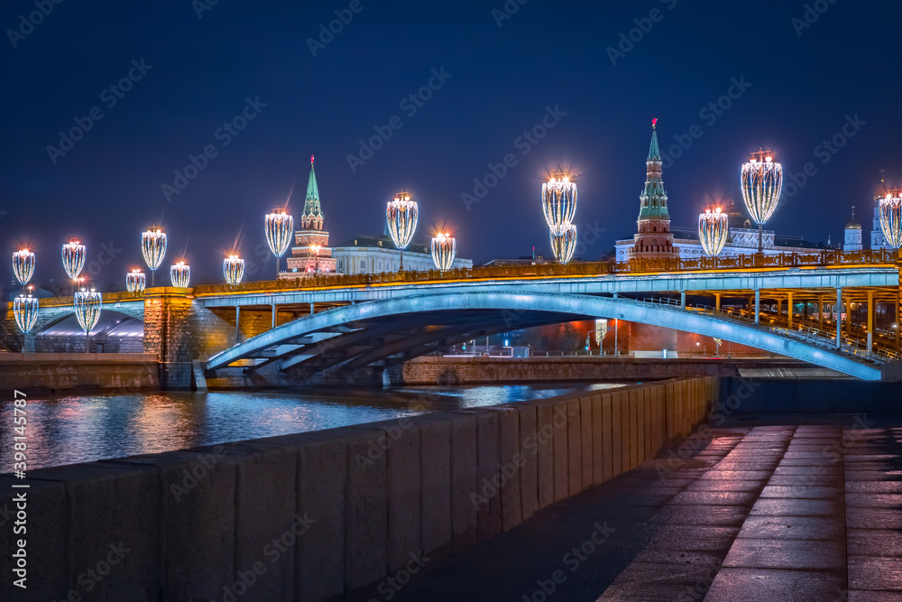 Obraz premium Moscow in the winter evening. Kremlin in Russia. Lanterns with Christmas garlands over Moscow River. Capital of the Russia Federation on New Year's Eve.