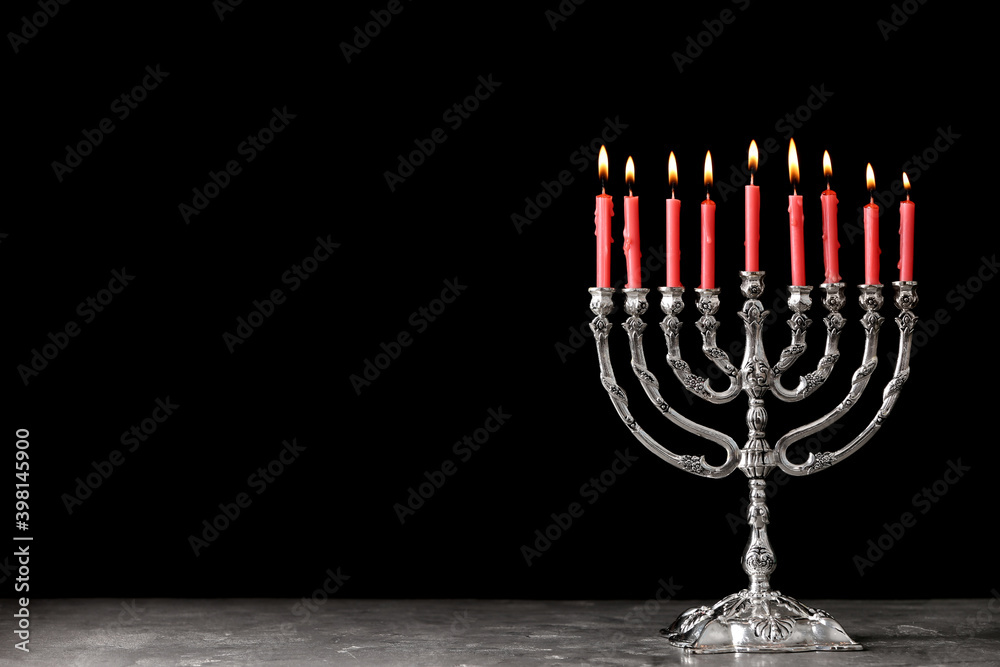 Silver menorah with burning candles on table against black background, space for text. Hanukkah celebration