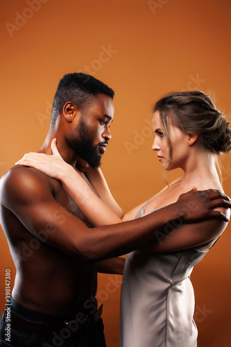 young pretty couple diverse races together posing sensitive on brown background, lifestyle people concept