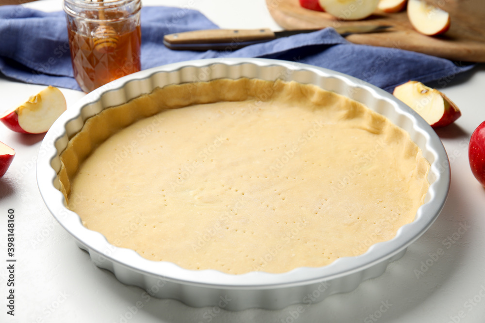 Baking dish with dough for traditional English apple pie on white table, closeup Baking dish with dough for traditional English apple pie on white table, closeup