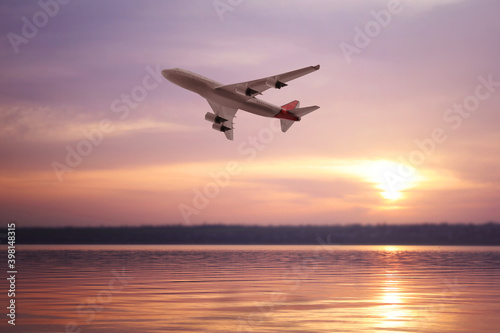 Modern airplane flying over river during sunset © New Africa