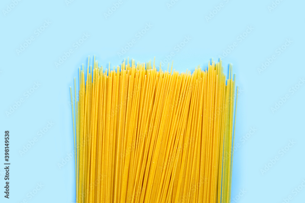 Yellow long spaghetti on blue background. Copy space
