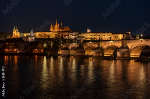 . prague castle and charles bridge and st. vita church lights from street lights are reflected on the surface of the vltava river in the center of prague at night in the czech republic © svetjekolem