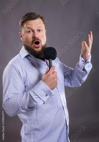 Bearded emotional singer with microphone dressed in shirt studio portrait. photo