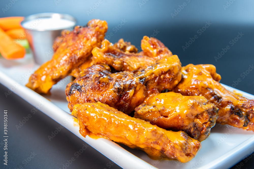 Delicious sweet spicy chicken wings piled on a plate makes the mouth water and the stomach growl. Delicious sweet spicy chicken wings piled on a plate makes the mouth water and the stomach growl.