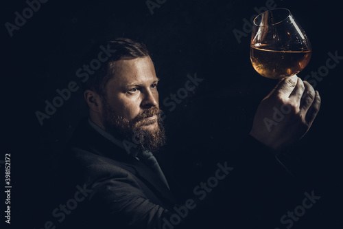 Solid confident bearded man in suit with glass of whisky