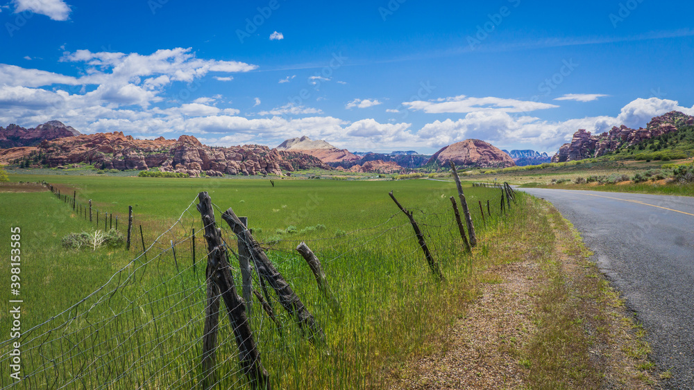 Fields and fence alon the road, with in the background the rock formations of Kolob Terrace in Zion National Park, Utah