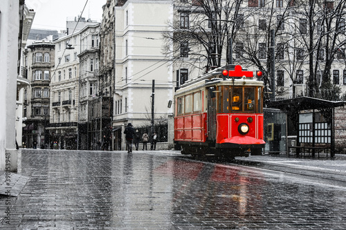 Red nostalgic tram is moving on the Istiklal street in winter day with snow. Istiklal Street is the most popular destination in Beyoglu, Taksim, Istanbul photo